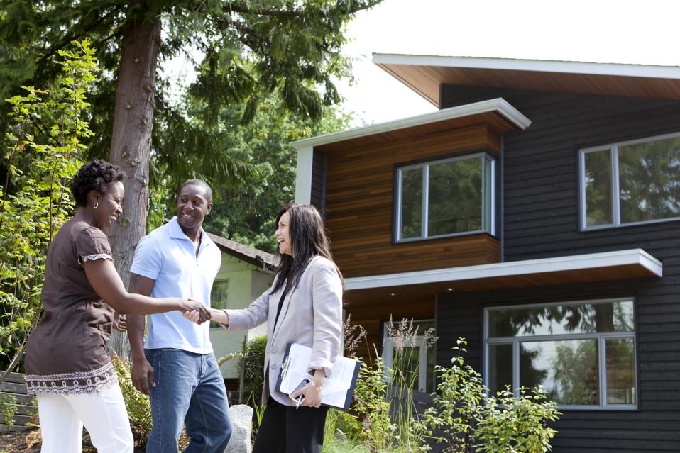 Realtor greeting clients in front of a home